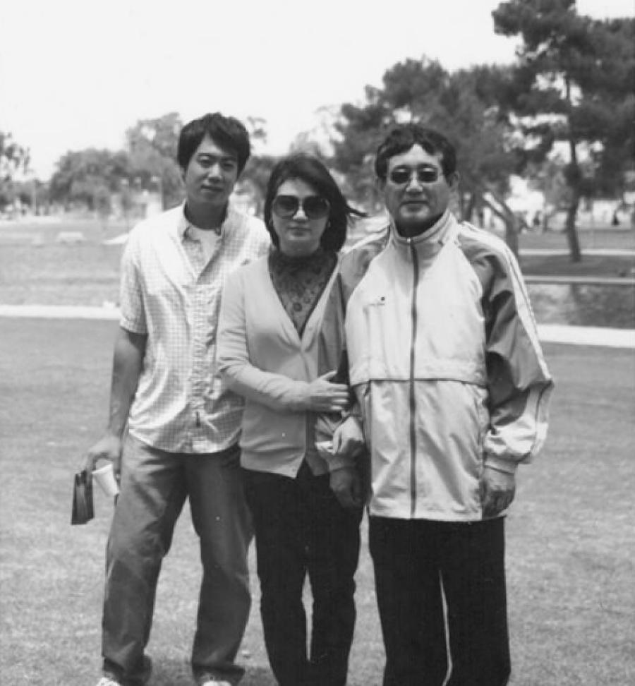 Three people pose together on a lawn in a black-and-white snapshot likely taken in Los Angeles in the 1970s or 1980s.